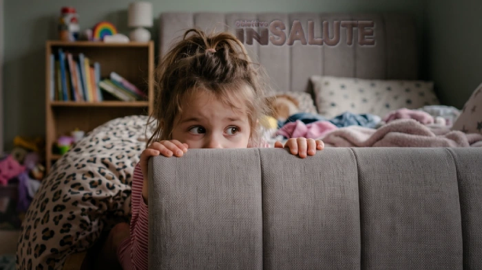 Bambina nella culla che si sporge dalla spalliera con gli occhi sbarrati