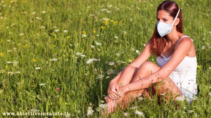 Donna con la mascherina, seduta in mezzo a un prato fiorito