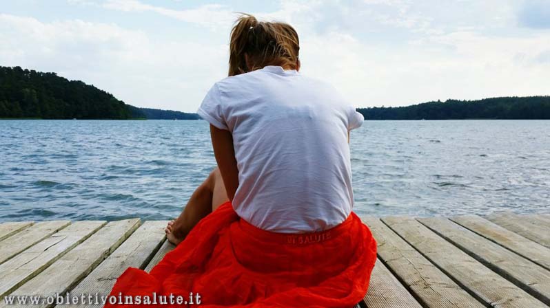 Donna seduta su un pontile mentre guarda il mare