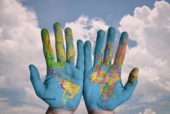 Due mani affiancate di palmo con su disegnata la cartina geografica del mondo