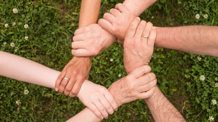 Diverse braccia agganciate tra loro, dalla presa delle mani che formano una rete