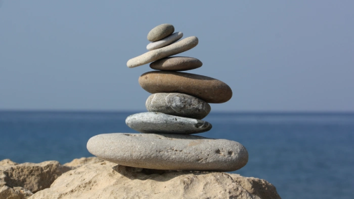 Composizione artistica di pietre levigate dall'acqua posizionate in un quasi irreale equilibrio su uno scoglio in riva al mare