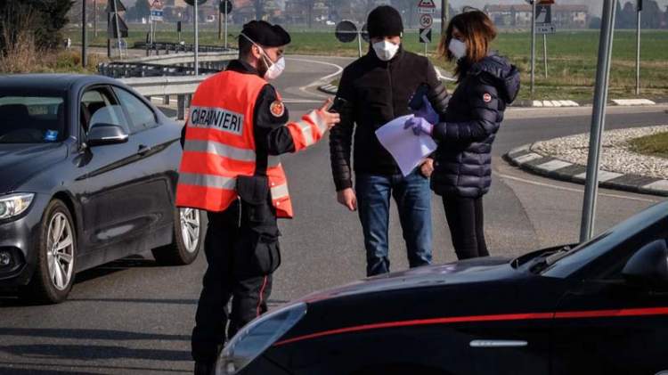 Carabiniere con la mascherina controlla l'autocertificazione di una coppia con la mascherina
