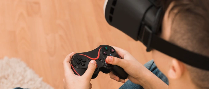 Un adolescente è chiuso nel buio della propria cameretta mentre gioca ai videogames con un visore 3d