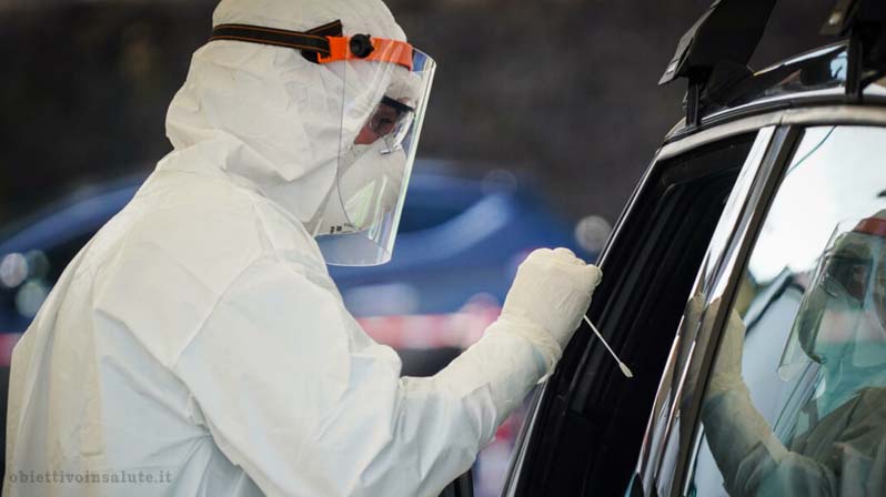 Infermiere protetto che fa il test anti-covid a un paziente attraverso finestrino dell'auto