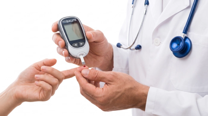 Dottore verifica a una paziente la presenza del diabete con il misuratore della glicemia