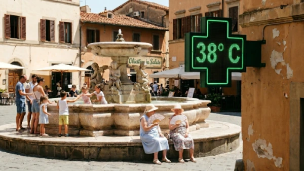 Una piazza italiana con una fontana nelle cui vicinanze ci sono degli adulti con dei bambini che giocano. Sui bordi della fontana ci sono due donne anziane con cappellino chiaro che sventolano un ventaglio per il caldo. In primo piano, sulla destra la classica insegna luminosa (sporgente) di una farmacia che segna la temperatura di 38° C