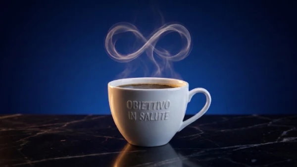 Fotografia realistica di una tazza di porcellana bianca piena di caffè scuro, appoggiata su una superficie riflettente nera, su sfondo blu profondo. Un filo di vapore bianco e luminoso sale dalla tazza, arricciandosi naturalmente e formando un perfetto simbolo dell'infinito sospeso nell'aria. Illuminazione soffusa e cinematografica. Immagine elegante e raffinata che simboleggia l'antico meccanismo cellulare attivato dalla caffeina, legato al rallentamento dell'invecchiamento.