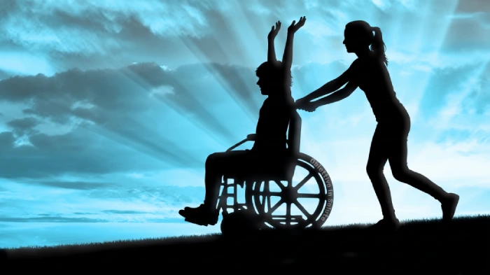 Ragazzo disabile su una carrozzella viene spinto da una ragazza